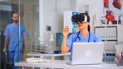 Medical nurse experiencing virtual reality using vr goggles in hospital office. Therapist using...