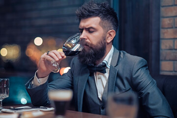 Man sit in cafe drinking alcohol, rest in restaurant with wine glass. Businessman with long beard drink in club.