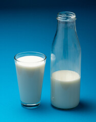 Glass of fresh milk and bottle of milk isolated on blue background.