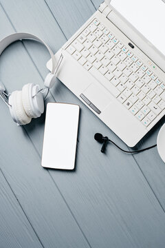 Headphone, Laptop, smartphone and microphone on grey wooden background. Remote work, Office Workplace concept. Top view. Social network Voice talk Live webinar. Audio chat, Podcast. Clubhouse