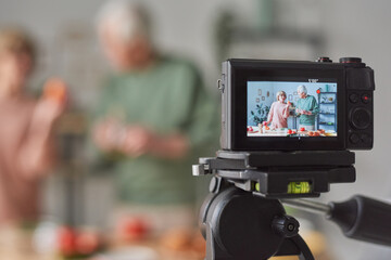 Two senior bloggers telling about food and shooting blog for camera in the kitchen