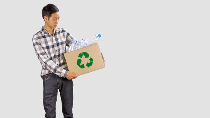 Young asian man holding a paper box of plastic bottle with recycle sing standing on empty space of...