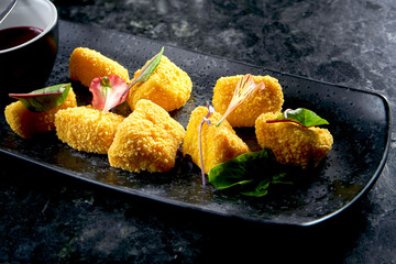 Camembert fries with jam served in a black plate on a dark background. Restaurant snack. Food pub