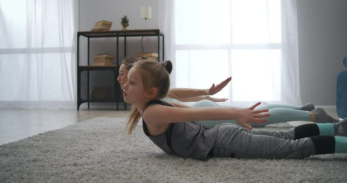 home fitness training of sporty family, mother and daughter are training together in living room, gymnastics