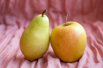 Pear and apple on a pink fabric background.Fresh fruits in minimal trend concept