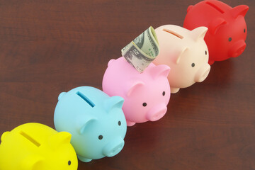 Many colorful piggy banks on and money wooden background. Choosing investment and savings funds concept.