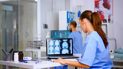 Assistant expertise doctor in medical uniform examining digital x-ray film and writing diagnosis on clipboard in hospital clinic, notting treatment for patient. Radiologist analysing radiography
