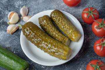 A white plate of pickled cucumbers with tomatoes