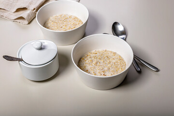 Classic Oatmeal with milk in white bowls. Delicious and healthy breakfast. Ideas and recipes for home meals.