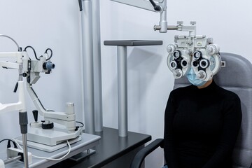 Young patient eye examination at optometrist using phoropter