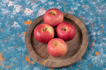 Apples in a wooden plate on a blue texture background