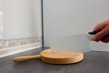 A wide-angle shot of a knife being held on a wooden cutting board in the kitchen