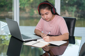 Education learning online concept, Teenage student wear headphone  using computer studying online. New normal style. Teen girl using computer laptop to self learning online.