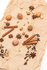 Fototapeta na wymiar Cinnamon sticks, star anise, allspice and cardamom, lychee and walnut on brown paper