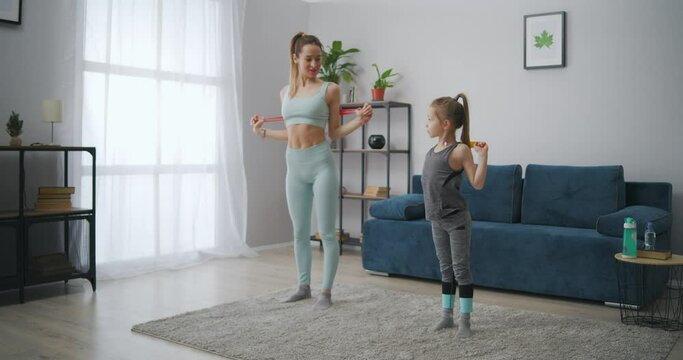 slender sporty woman is training her little daughter at home, instilling good habits and healthy lifestyle in child