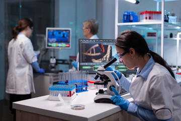 Biochemist scientists studying reaction of virus on microscope in laboratory. Research chemists...