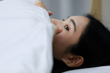 Fototapeta na wymiar Asian woman mattress on the bed peeking at a female partner in the bedroom at home. Concept in love homosexual lesbian lgbt, lgbtq, lgbtq+.