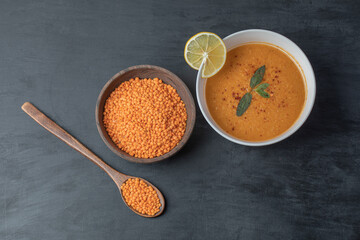 A wooden bowl of lentil beans with soup and slice of lemon