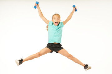 Adorable female child holding dumbbells and jumping