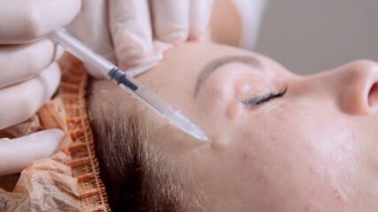 Cosmetologist making treatment procedure to patient. Beautician makes injections in the woman’s face. Mesotherapy. Doctor's hands in white medical gloves put injections in female face.