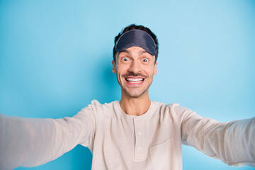 Self-portrait of nice cheerful funny brunet guy wearing sleep mask having fun good mood isolated over bright blue color background
