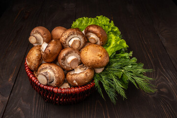 mushrooms in a basket with lettuce and herbs on a dark wooden table