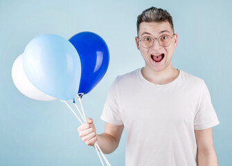 A happy man celebrates the anniversary of a business company, comes to a corporate party, carries colorful balloons, wears glasses. Cheerful student comes to the outgoing party