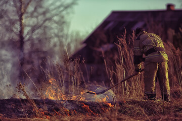 firefighter puts out grass / forest fire, dry grass burns, wind blows