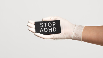 Closeup of the hand in a white sterile glove holding a card with text - STOP ADHD