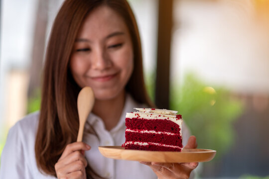 Closeup image of a female chef baking and eating a piece of red velvet cake in wooden tray