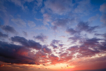 Fototapeta na wymiar Calm sea with sunset sky and sun through the clouds over.