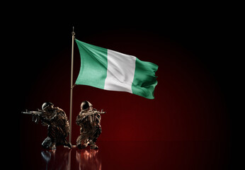 Concept of military conflict. Waving national flag of Nigeria. Two soldier statue guards defending the symbol of country against red wall