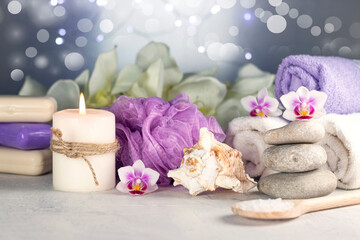 Obraz na płótnie Canvas Massage stones, seashell, burning candles, rolled towels, soap, massage oil, sea salt, flowers, abstract lights. Spa resort therapy composition