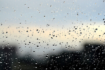 Abstract photo background. Rain drops on window. Selective focus, rainy city background. Water drops on glass. Rainy weather, blur wallpaper