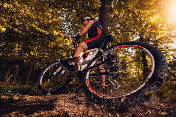 Fototapeta na wymiar Cyclist riding mountain bike on trail at sunset
