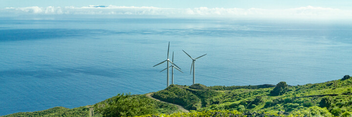 Three wind turbines on the coast of the Canary Island of La Palma, Spain, in the background the Atlantic Ocean - 416479577