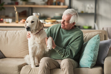 Senior man sitting on sofa together with his dog during leisure time at home