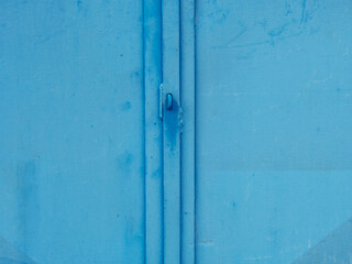 Steel padlock eye on vintage metal warehouse door. Weathered blue paint