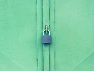 Secured garage door. Locked lock on green painted metal door.