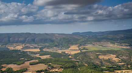 Fototapeta na wymiar Mosaic landscape with cereal crops and pine trees groves. Photo taken from the Font Roja Natural Park, province of Alicante, Spain