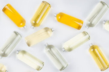 Abstract cosmetic pattern of lying bottles with different pale colors liquid, silver cap on white background, top view.