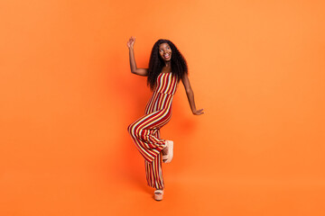 Full length photo of dark skin happy pretty lady look empty space good mood isolated on orange color background