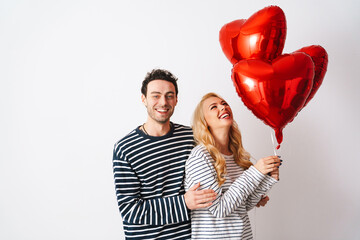 Happy romantic couple laughing while posing with heart balloons