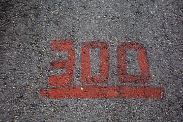 Grey asphalt road with red painted number three hundred