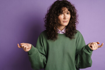Brooding brunette curly girl thinking and gesturing with hands