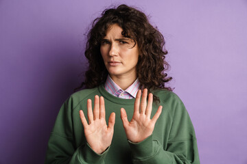 Brooding brunette girl frowning and doing stop gesture with hands