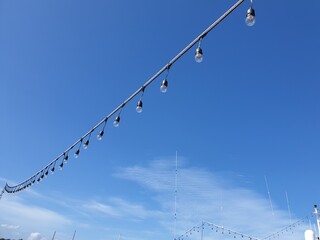 Light bulbs on string wire against the sky