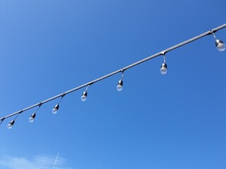 Light bulbs on string wire against the sky