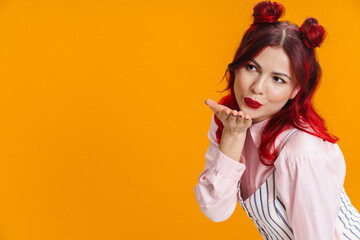Fototapeta premium Beautiful girl with red hair blowing air kiss at camera