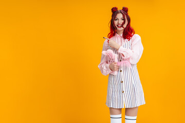 Joyful girl pointing finger aside while posing with diary and feather